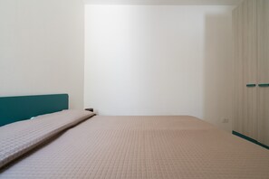 A room with a bed, a teal headboard, and a wardrobe with two doors.