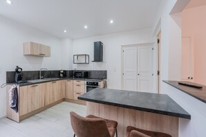 A modern kitchen with wooden cabinets, a black countertop, and a built-in microwave.