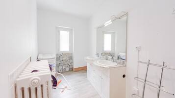 A modern bathroom with two sinks, a large mirror, and a radiator.