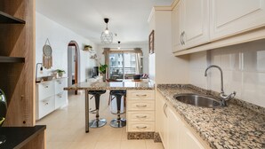 A kitchen with a granite countertop, stainless steel sink, and bar stools. - Vacation Apartment 'Apto Sol Paraiso Sunset View' with Shared Pool, Private Terrace and Wi-Fi (Adeje)