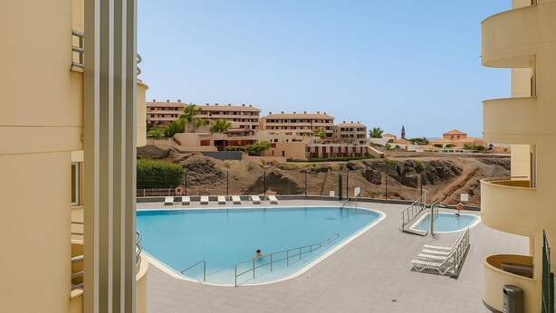 A swimming pool with a curved design, a small adjacent pool, and a view of residential buildings in the background. - Vacation Apartment 'Apto Sol Paraiso Sunset View' with Shared Pool, Private Terrace and Wi-Fi (Adeje)