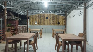 A restaurant interior with bamboo decor, wooden tables and chairs, and a tiled floor. - Rinjani Terrace Cottage (Kotaraja)