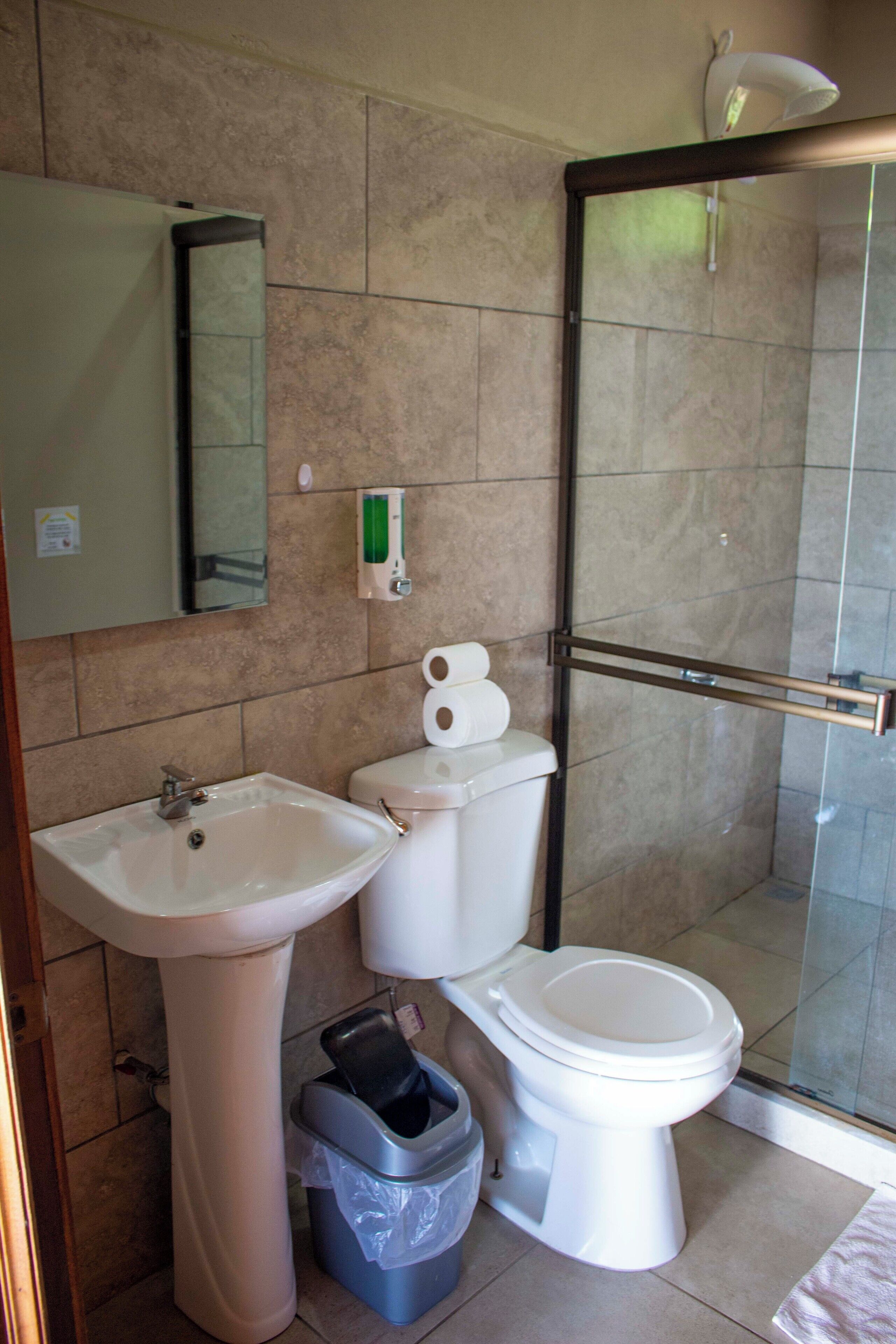 A bathroom with a sink, toilet, and glass shower enclosure.
