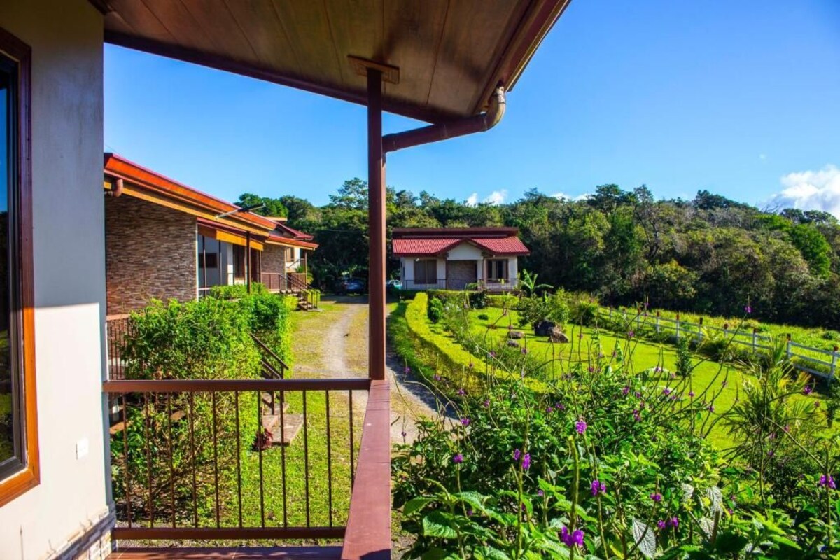 A balcony with a view of a landscaped garden and two buildings.