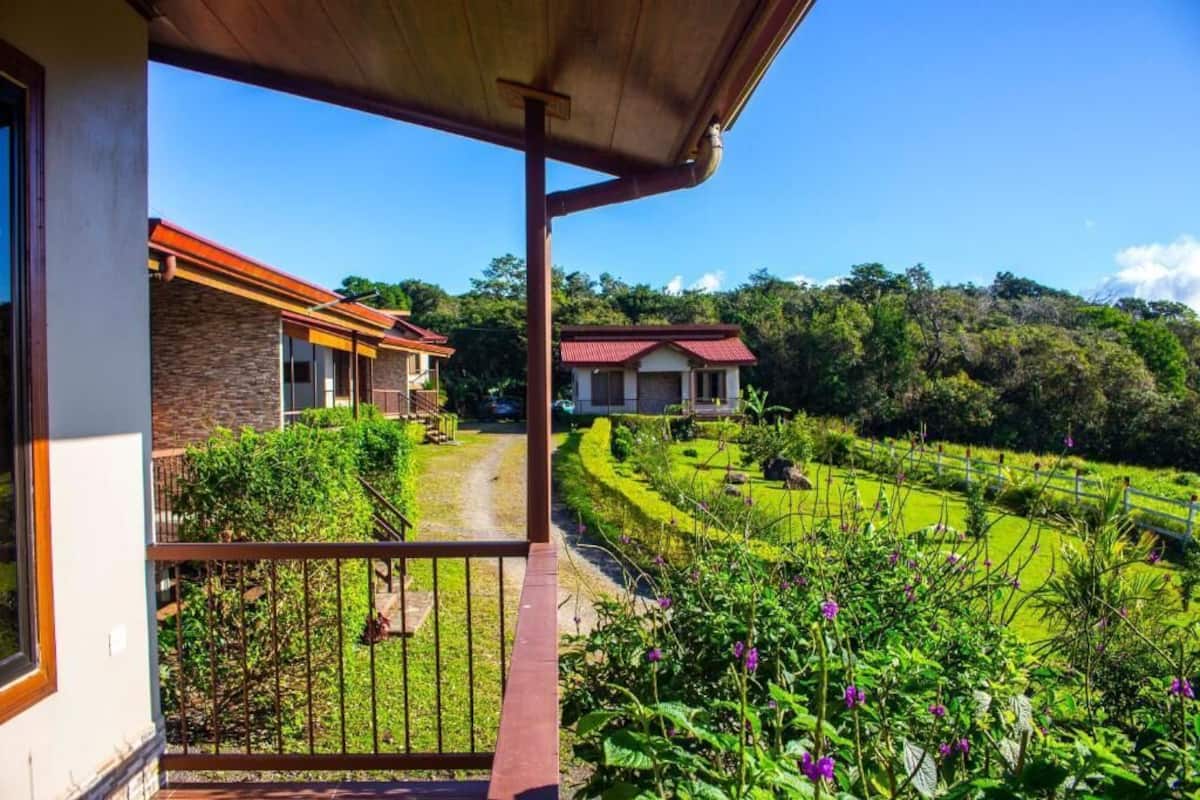 A balcony with a view of a landscaped garden and two buildings.