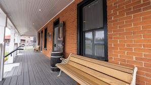 A covered outdoor area with a wooden bench, a trash can, and a window. - ATLANTIC HOTEL (Alexandria)