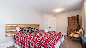 A bedroom with a bed, wooden headboard, a dresser, and a chair.