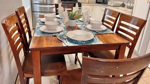 A dining table set for four with white plates and bowls, a central plant, and a blue placemat.