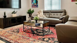 A living room with a sofa, coffee table, TV, and decorative plants.
