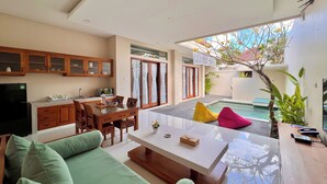 Uma sala de estar moderna com área de jantar, cozinha e piscina.