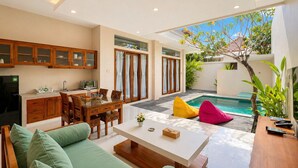 Um espaço de estar moderno com área de jantar, cozinha e piscina.