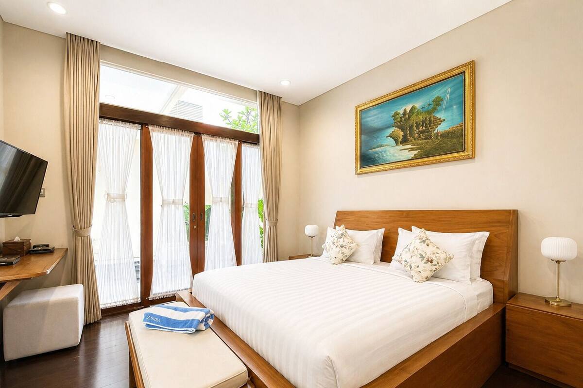 Une chambre d’hôtel avec un grand lit, une télévision, un bureau et un tableau au mur.