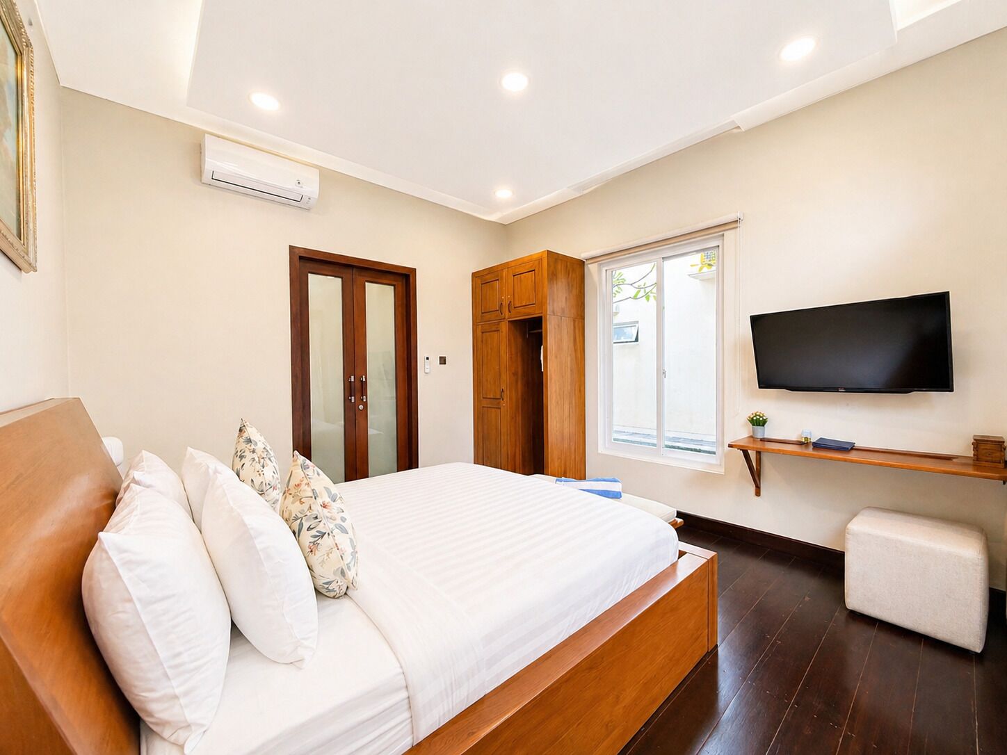 A bedroom with a bed, a TV, a wardrobe, and a window.