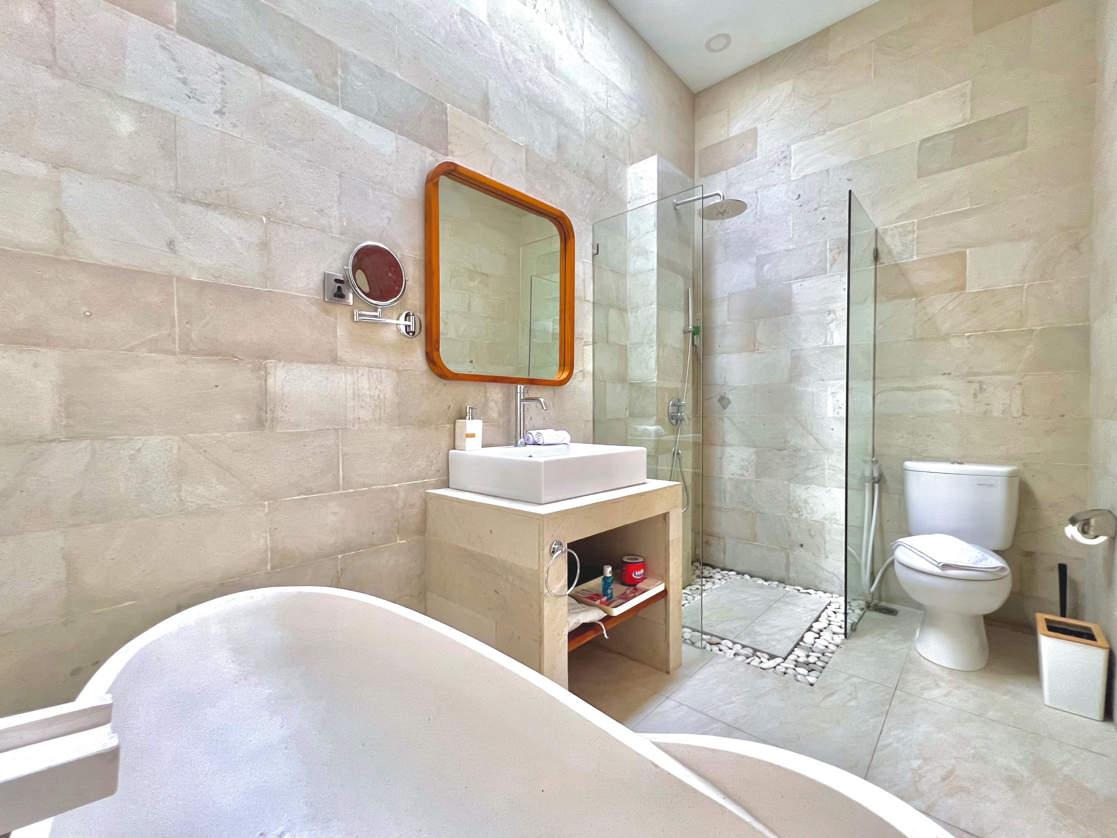 A modern bathroom with a freestanding bathtub, a glass-enclosed shower, a toilet, and a sink with a mirror above it.