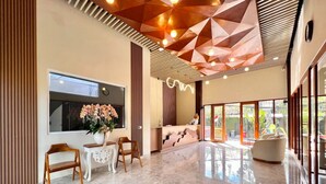 Interior moderno com design geométrico no teto, uma janela ampla e uma área de estar com uma mesa redonda.