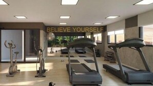 Un gimnasio moderno con cintas de correr, bicicletas estáticas y un cartel motivacional que dice 'BELIEVE YOURSELF'.