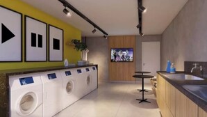 Una cocina moderna con lavadora integrada, una barra y una amplia pantalla de televisión.