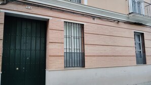 A building with a brick facade, a black metal gate, and two windows with metal bars.