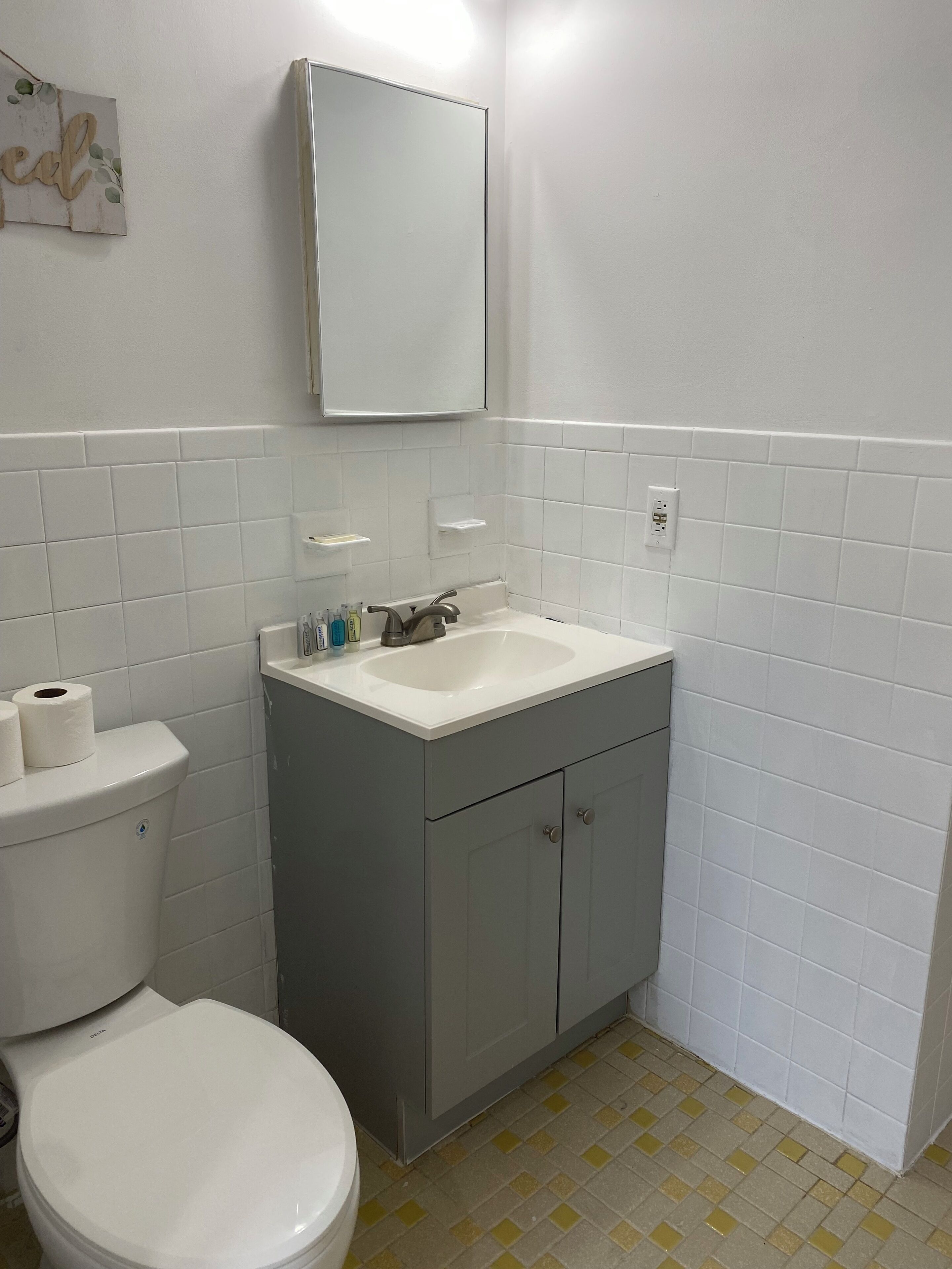 Een badkamer met toilet, wastafel en spiegel.