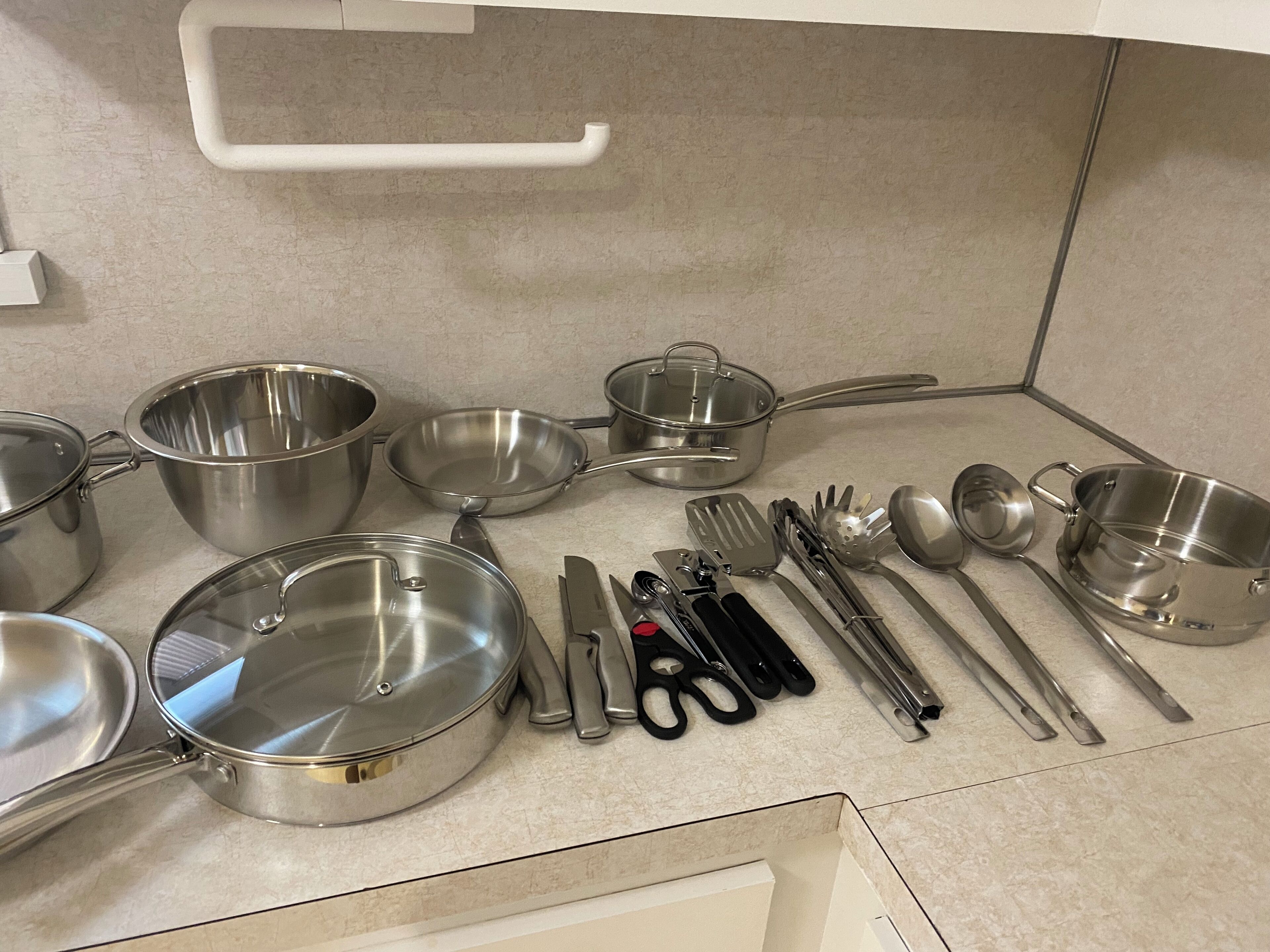 Een keuken met roestvrijstalen kookgerei, waaronder pannen, braadpannen en keukengadget.