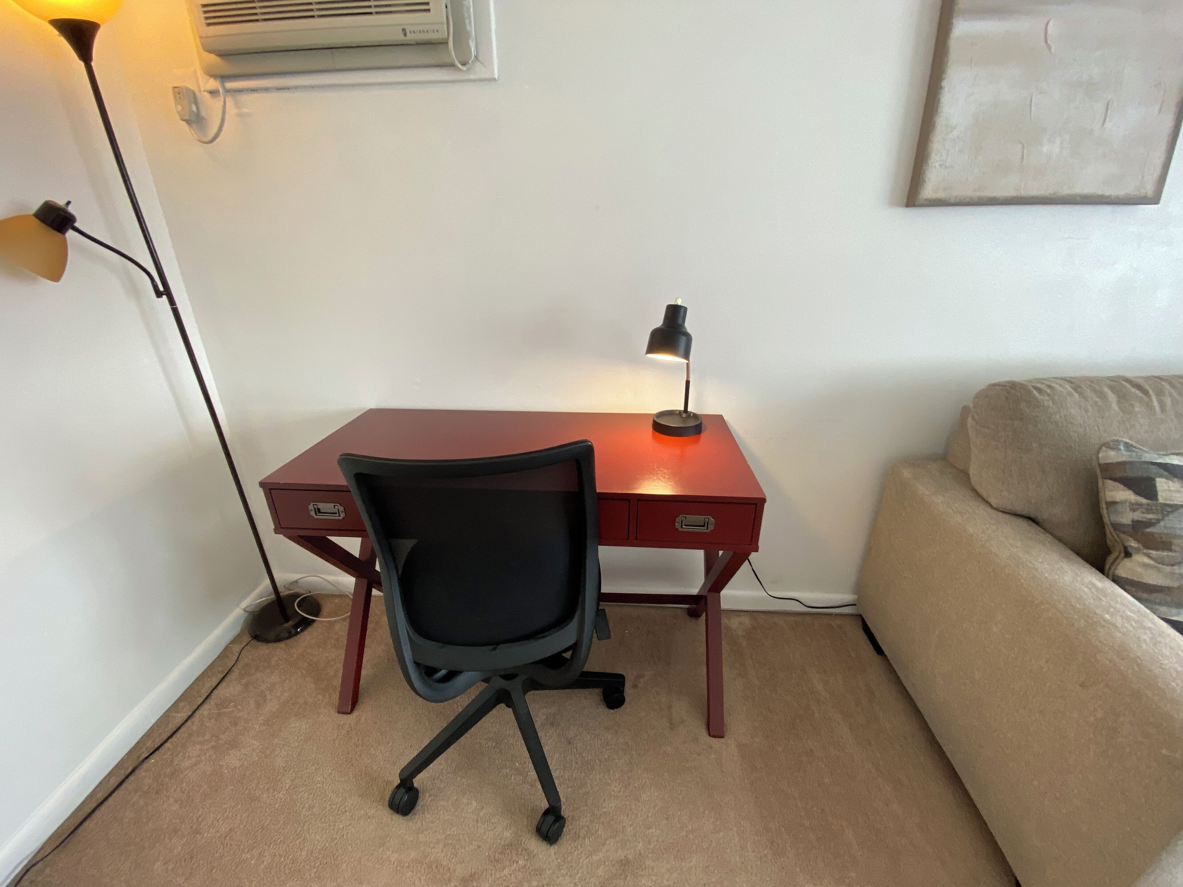 A small office space with a desk, chair, and a lamp.