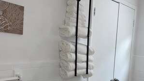 Ein Badezimmer mit weißen Fliesenwänden, einer weißen Tür und einem Handtuchhalter mit ordentlich gefalteten Handtüchern.