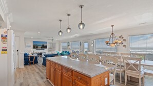 A spacious kitchen with a large island, wooden cabinets, and pendant lighting.