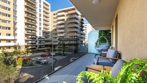 Un balcon donnant sur un parking et les bâtiments avoisinants.