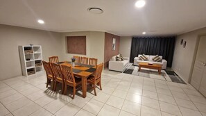 A living room with a dining table, chairs, a sofa, a coffee table, and a bookshelf.