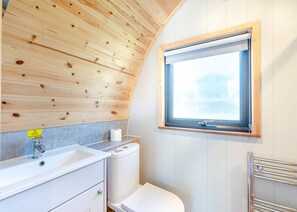 A bathroom with a wooden ceiling, a window, a sink, a toilet, and a towel rack. - Kyloe Glamping Pod (Pet Friendly) (Coldstream)