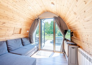 A cozy, wooden-paneled room with a sofa, a television, and a view of the outdoors.