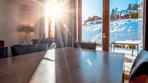A room with a large table, a sofa, and a view of a snowy mountain. - Residence Lipno by Interhome (Lipno nad Vltavou)