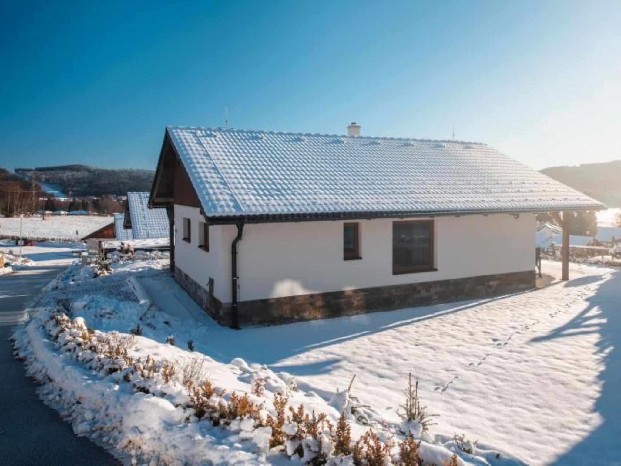 Yhden kerroksen talo, jossa on kalteva katto, pieni kuisti ja lumipeitteinen piha.