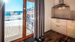 A kitchen with a view of a snowy landscape through a glass door. - Residence Lipno by Interhome (Lipno nad Vltavou)