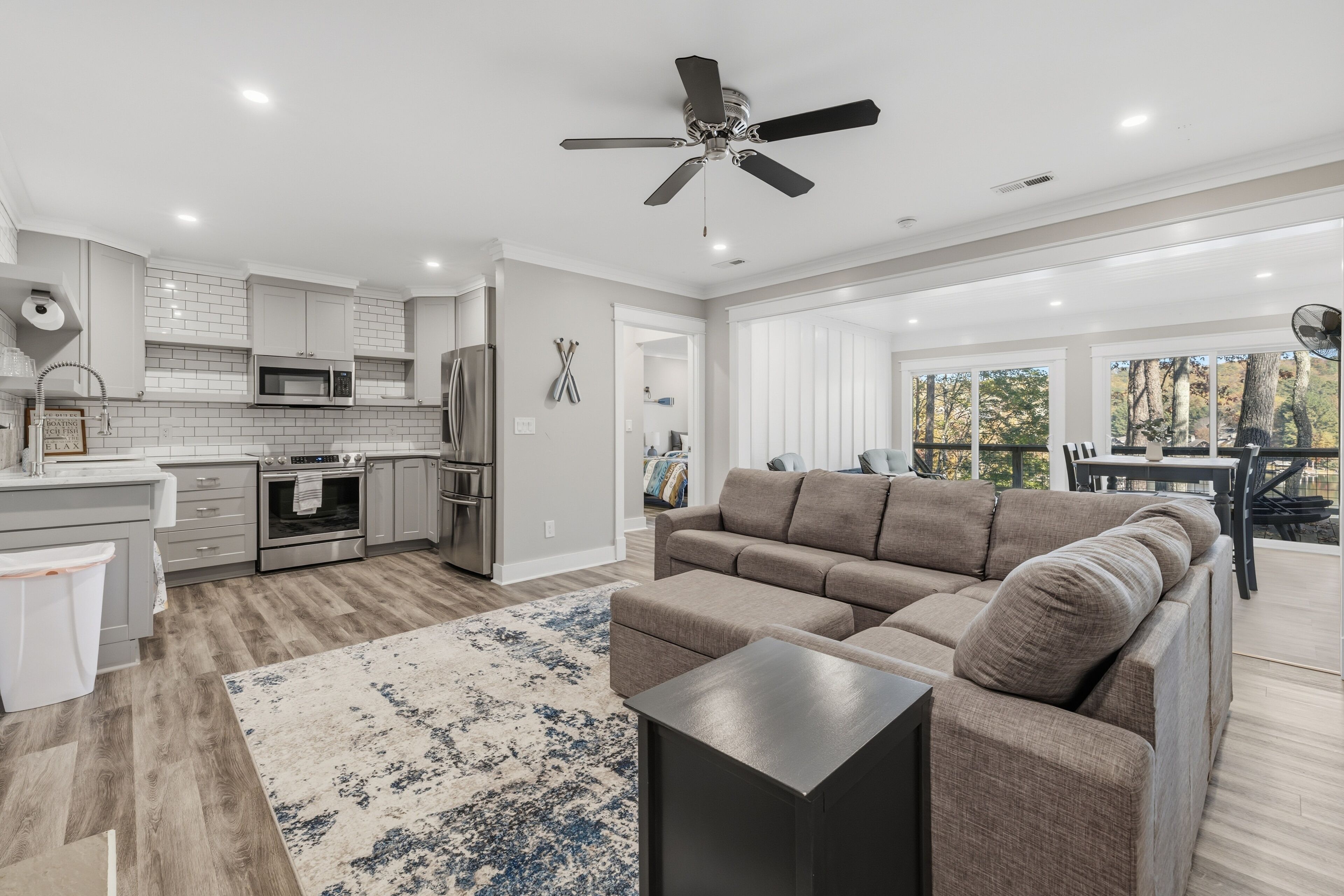A modern kitchen with white cabinets, stainless steel appliances, and a ceiling fan.