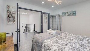 A modern bedroom with a large bed, a glass shower, and a staircase leading to an upper level. - Contemporary Monochrome Retreat With 4beds & POOL (Albuquerque)