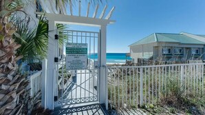 Una entrada con reja a una zona de playa, con un cartel que indica acceso privado para propietarios y huéspedes de Emerald Waters Village y Royal Seafront Townhomes.
