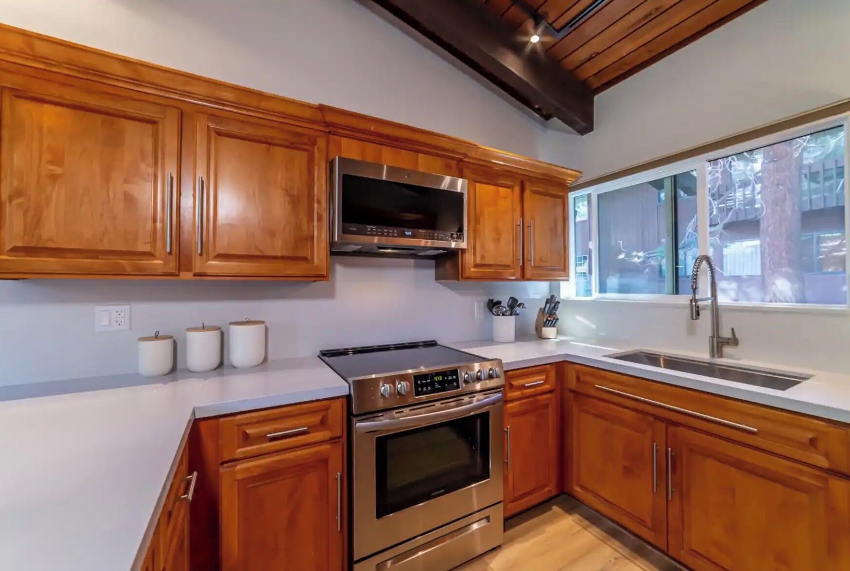 A kitchen with wooden cabinets, stainless steel appliances, a window, and a sink.
