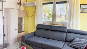 A living room with a grey sofa, a small table, a cabinet, and a window with curtains. - am Pälitzsee by Interhome (Rheinsberg)