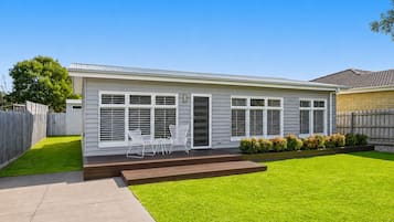 A single-story house with a front porch, a small deck, and a well-maintained lawn.