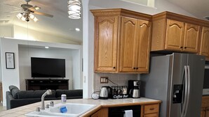 Una cocina moderna con armarios de madera, un refrigerador de acero inoxidable, una barra de café y un lavavajillas integrado.
