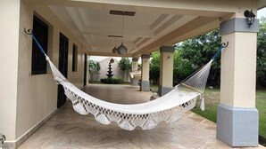 A covered outdoor area with a hammock, a fountain, and a tiled floor. - Apartamento Fresco y Seguro con Piscina y Terrazas, 1 Hora las Mejores Playas (Managua)