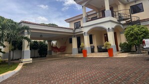 A two-story house with a covered patio and a balcony. - Apartamento Fresco y Seguro con Piscina y Terrazas, 1 Hora las Mejores Playas (Managua)