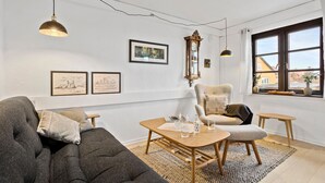 Ein gemütliches Wohnzimmer mit einer Couch, Sesseln, einem Holztisch und einem großen Fenster mit Blick.