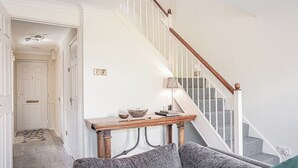 A staircase with white railings and a wooden handrail, leading to a landing with a table and a bowl. - Central 2BD with Garden and Free Parking (Cheltenham)