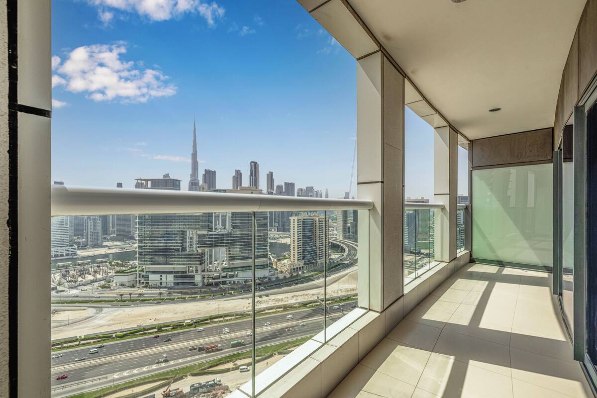 A balcony with a city view, large windows, and a modern interior.