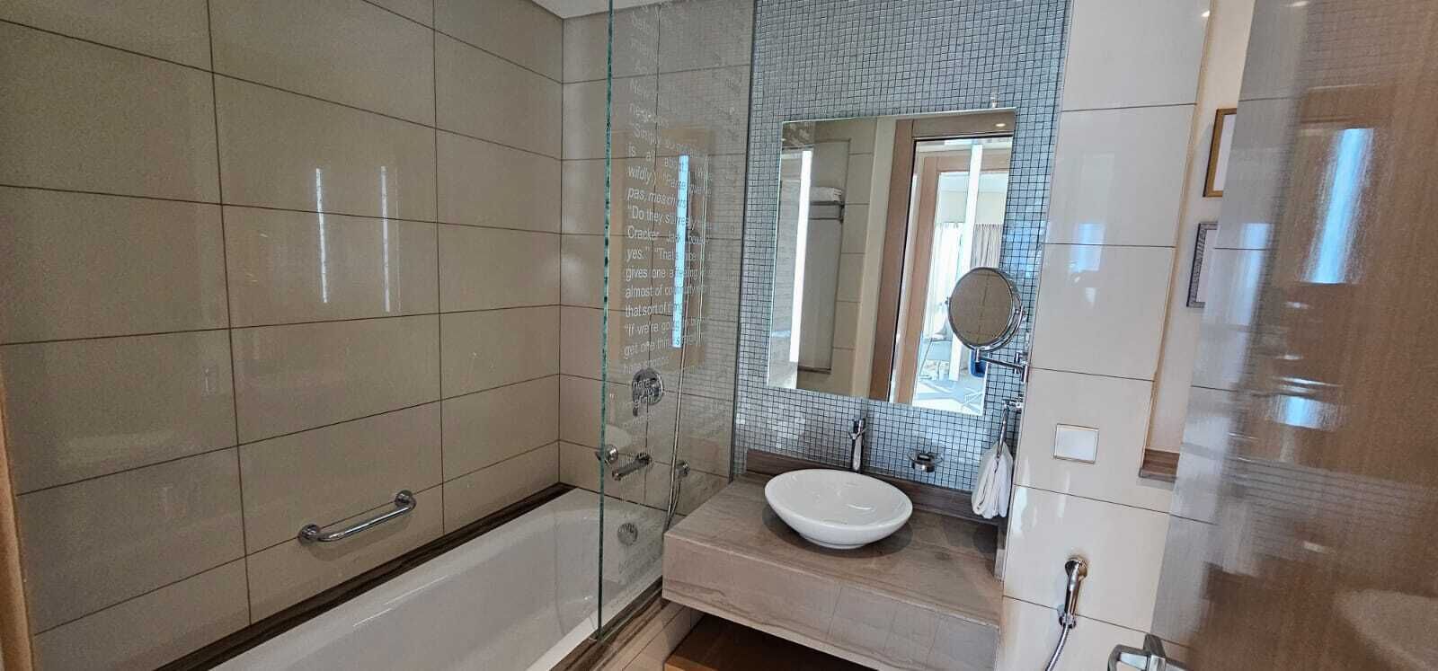 A modern bathroom with a glass shower enclosure, a white bathtub, and a vanity with a sink.