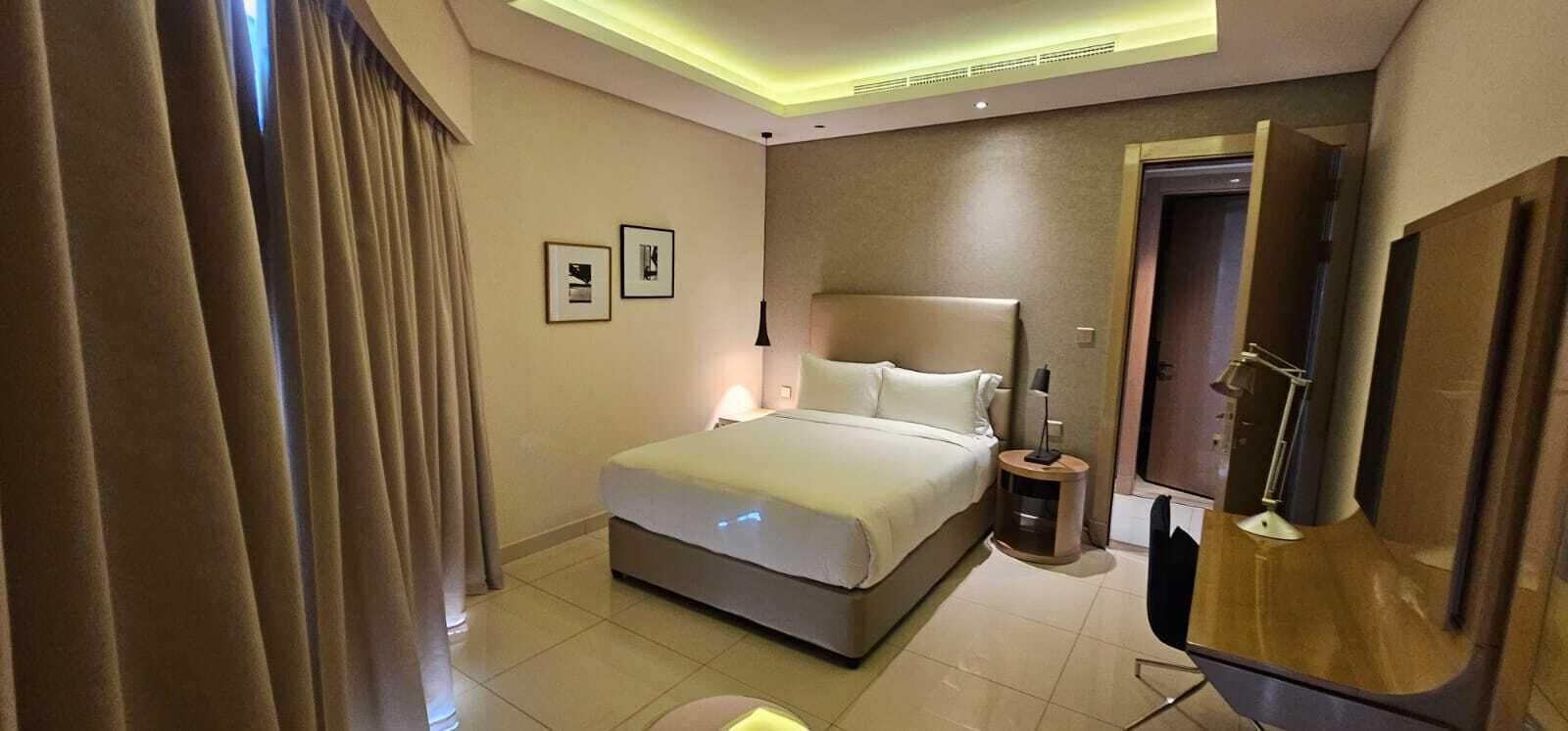 Una camera d'albergo moderna con un letto grande, comodini, una scrivania e una televisione.