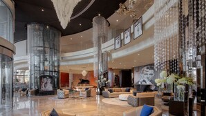 Eine großzügige Lobby mit hohen Decken, großen Kronleuchtern und modernen Möbeln.