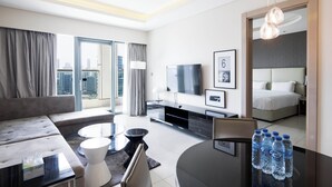 Ein modernes Hotelzimmer mit einer Couch, einem Esstisch, einem Fernseher und einem Bett.